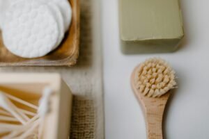 Close-up of eco-friendly bath products including soap and brush on a neutral background.